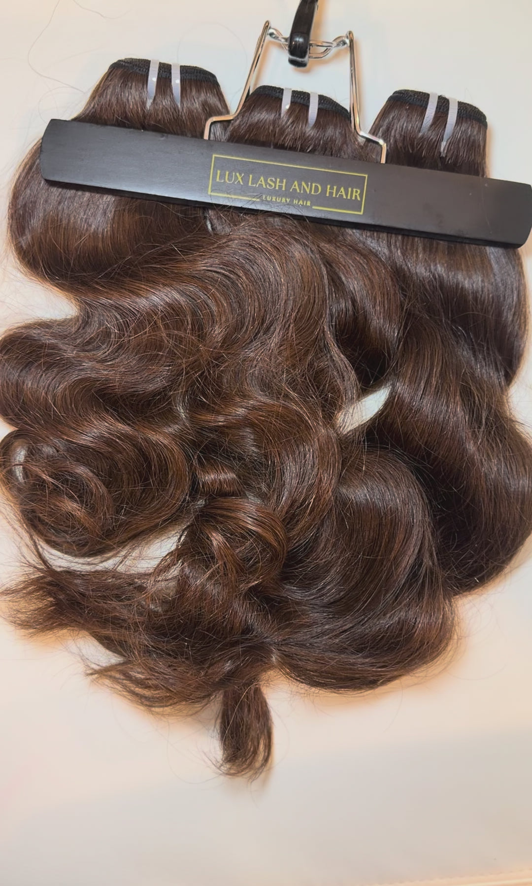 Video of Lux Lash and Hair Brown Sugar Luxe natural wave 3-bundle set in 16” and 18” lengths displayed on marble background.